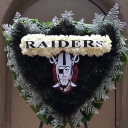 Heart-shaped funeral wreath with white flowers and a Raiders emblem