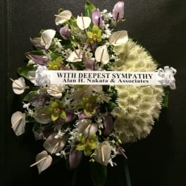 Sympathy wreath with white and purple flowers and a condolence ribbon