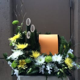 Floral arrangement with yellow and white chrysanthemums around an orange panel