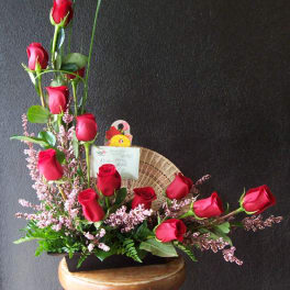 Red roses arranged in a low black container with pink filler flowers