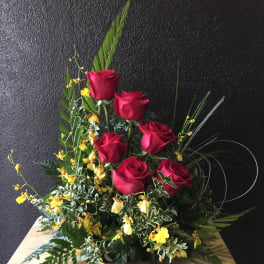Red roses with yellow accent flowers in a low arrangement