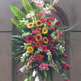 Tall standing floral spray with red, yellow, and pink blooms
