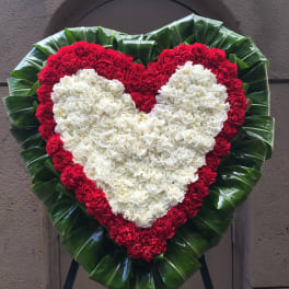 White heart on red heart Carnations with Ti leaves surround wreath - F30009