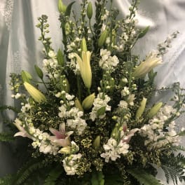 Tall white floral arrangement with lilies and small white blooms in a basket