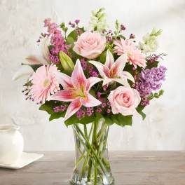 Pink roses and lilies arranged in a clear glass vase