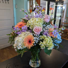 Mixed pastel bouquet in a clear glass vase with roses, hydrangeas, and gerbera daisies