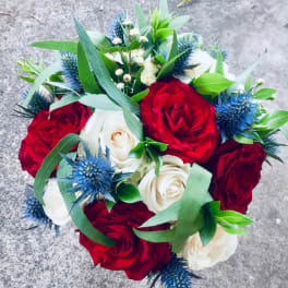 Bouquet of red and white roses with blue thistle accents