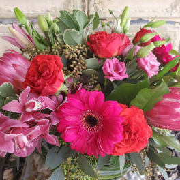 Mixed bouquet with pink orchids, red roses, and a bright pink gerbera daisy