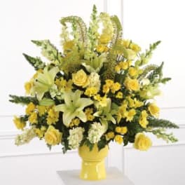 Yellow floral arrangement in a yellow vase with lilies and roses