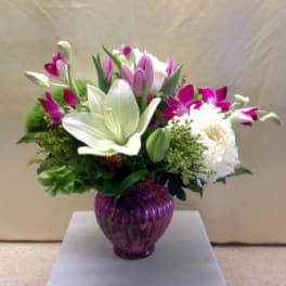Bouquet of white lilies and purple tulips in a purple glass vase
