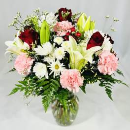 Bouquet of lilies, roses, carnations, and daisies in a glass vase