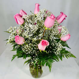 Pink roses arranged with white baby's breath in a glass vase