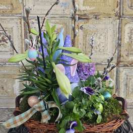 Easter basket with lilies, purple flowers, and decorated eggs