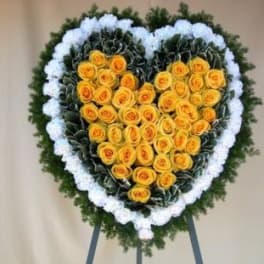 Heart-shaped floral wreath with yellow roses and white edging on an easel