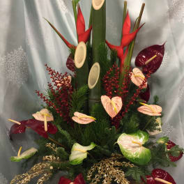 Tropical arrangement with red and pale anthuriums in a tall vase