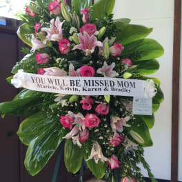 Standing sympathy spray of pink roses and lilies with a memorial ribbon