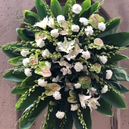 Large white floral standing spray with broad green leaves
