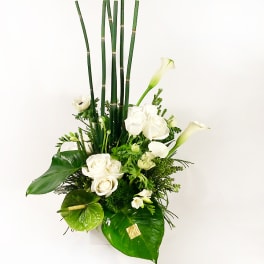 White roses and calla lilies arranged with tall bamboo stems