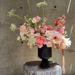 Pink and peach mixed flowers arranged in a black vase