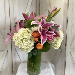 Pink lilies and white hydrangeas in a tall glass vase