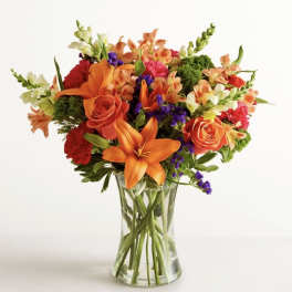Mixed bouquet of orange and red flowers in a clear glass vase
