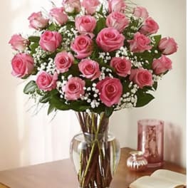 Pink roses arranged in a clear glass vase with white filler flowers