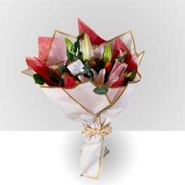 Bouquet of pink and white lilies wrapped in white paper with gold trim