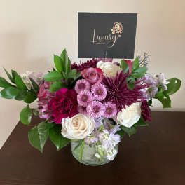 Pink, white, and purple flower arrangement in a clear glass vase