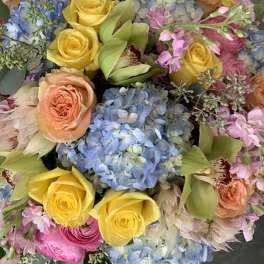 Bouquet of yellow roses, blue hydrangeas, and pink flowers