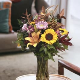 Bouquet of sunflowers, lilies, and mixed blooms in a glass vase