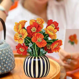 Orange and red flowers in a striped ceramic vase on a table
