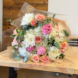 Bouquet of pink and white roses with white chrysanthemums wrapped in clear paper