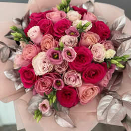 Bouquet of pink and red roses with pale wrapping and metallic leaves