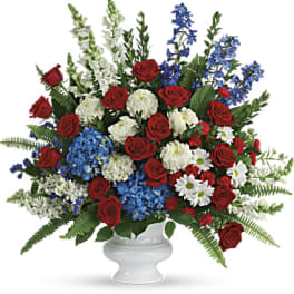 Red roses, blue flowers, and white blooms in a white vase