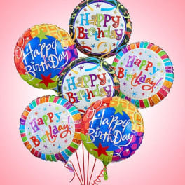 Cluster of colorful birthday balloons against a pink background
