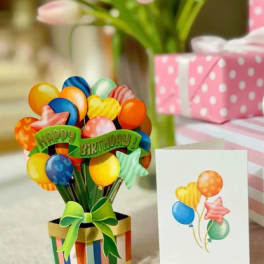 Birthday balloon bouquet in a striped gift box with a greeting card