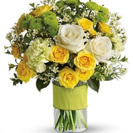 Yellow and white roses in a clear vase with green mums