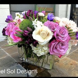 Mixed bouquet of pink, purple, and white flowers in a glass vase