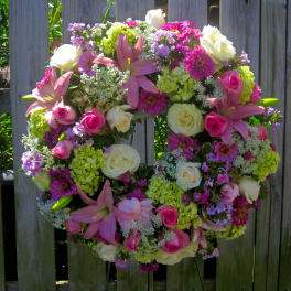 Heart-shaped floral wreath with pink lilies, roses, and white blooms