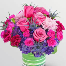 Pink roses and carnations with purple hydrangeas in a green striped vase