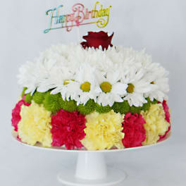 Colorful birthday cake topped with flowers and a rose