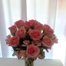 Pink roses and small striped flowers in a clear glass vase