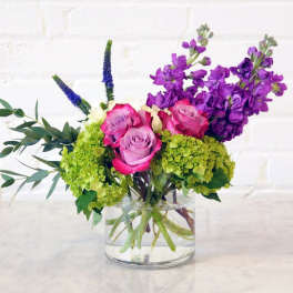 Bouquet of pink and lavender roses with purple flowers in a glass vase