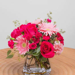 Pink roses and gerbera daisies arranged in a clear glass vase