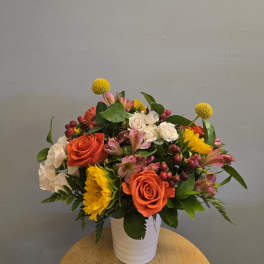 Mixed bouquet of orange and white roses with yellow blooms in a white vase
