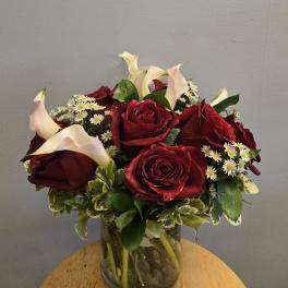 Bouquet of red roses and white calla lilies in a glass vase