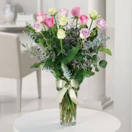 Bouquet of pink and white roses in a clear glass vase with a ribbon