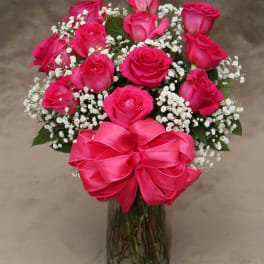 Pink roses with baby's breath in a glass vase and pink bow