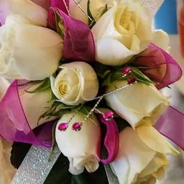 Bouquet of white and pale yellow roses with pink ribbon accents