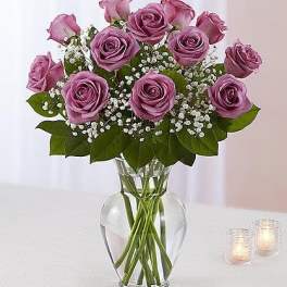 Lavender roses arranged in a clear glass vase with baby's breath